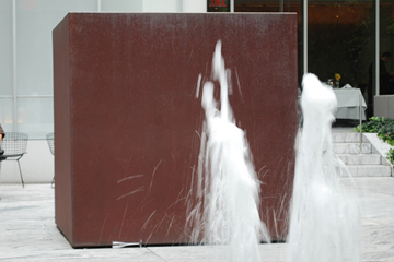 WATER JETS AND R. SERRA (RICHARD SERRA, BERLIN BLOCK FOR CHARLIE CHAPLIN, 1972, COR-TEN STEEL 200X200X200)